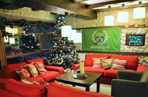 salon z choinką świąteczną i czerwonymi kanapami w obiekcie Pirin River Ski, Fun and Family w mieście Bansko