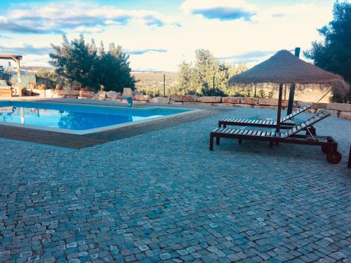 a hammock and a bench next to a swimming pool at Villa Monte da Alfarrobeira in Estói