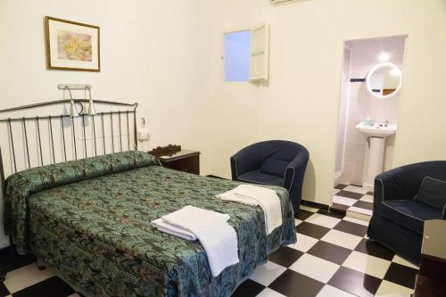 a bedroom with a bed and two chairs and a sink at Pensión San Benito Abad in Seville