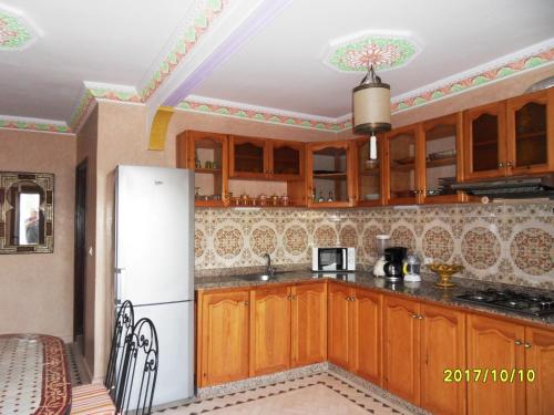 a kitchen with wooden cabinets and a white refrigerator at Appartement Terrasse Beau Soleil in Essaouira