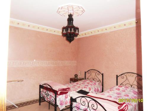 a bedroom with two beds and a chandelier at Appartement Terrasse Beau Soleil in Essaouira