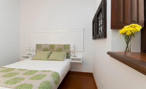 1 dormitorio con 1 cama y un jarrón con flores amarillas en Entre2mezquitas 6, en Córdoba