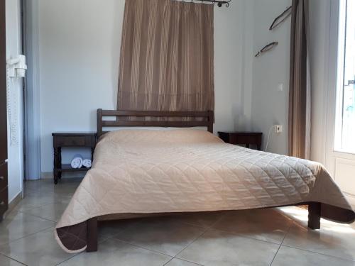 a bedroom with a bed with a tan comforter at Angelos Rooms in Irakleia