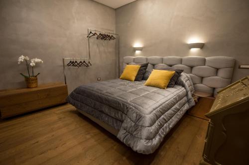 a bedroom with a large gray bed with yellow pillows at Civico Cinque Home Luxury Apartment in Salerno