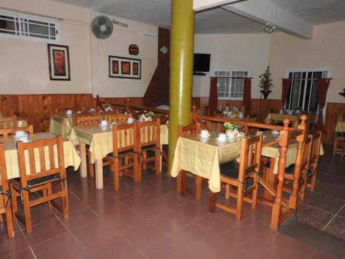 een restaurant met houten tafels en stoelen en een gele paal bij Hotel Atlántico Residencial in Santa Teresita