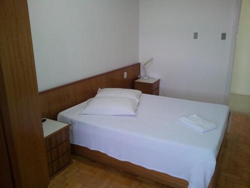 a bedroom with a white bed with a wooden headboard at City Hotel PF in Passo Fundo