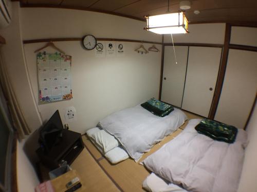 a room with two beds and a clock on the wall at Kenroku Haitsu 205 in Kanazawa