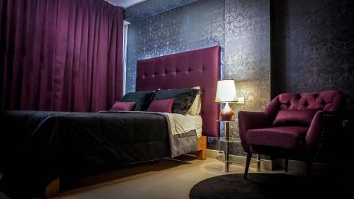 a bedroom with a purple bed and a chair at Hotel Venecia in Huánuco