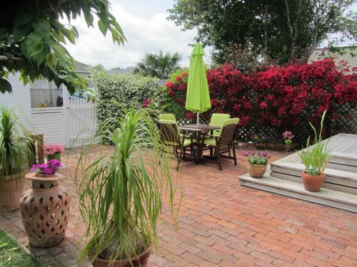 a patio with a table and chairs and a green umbrella at Welbourn Accommodation in New Plymouth