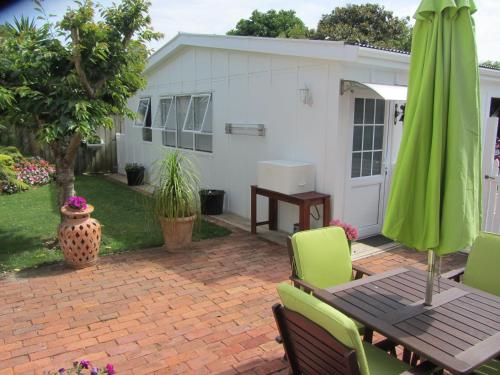 a patio with a table and a green umbrella at Welbourn Accommodation in New Plymouth