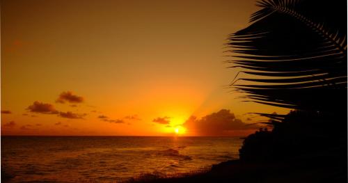 a sunset on the ocean with the sun setting at Inchcape Seaside Villas in Christ Church