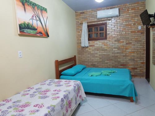 a bedroom with two beds and a brick wall at Chalés Pipa in Pipa