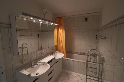 ein Badezimmer mit zwei Waschbecken, einer Badewanne und einem Spiegel in der Unterkunft Casa Pramalinis - Manstein in Davos