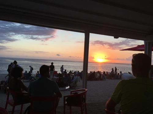 a group of people sitting on the beach watching the sunset at Le Chalet dAZAE in La Rivière