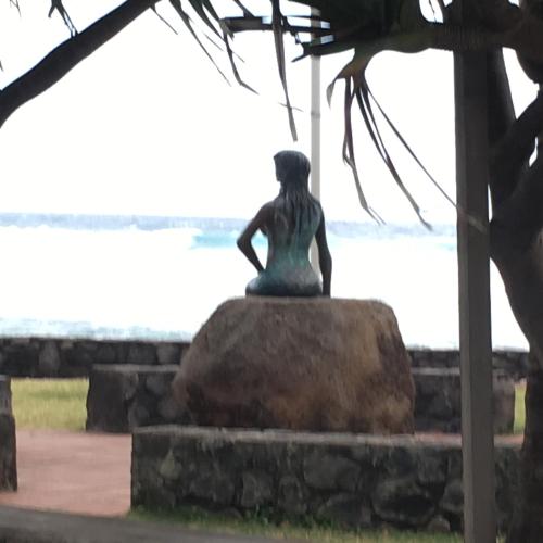 a statue of a woman sitting on a rock near the water at Le Chalet dAZAE in La Rivière