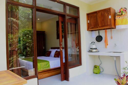 1 dormitorio con 1 cama y puerta de cristal en Manwarsa Guest House, en Ubud