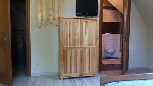 - une chambre avec une télévision au-dessus d'un meuble en bois dans l'établissement Noclegi w centrum Sienkiewicza, à Zakopane