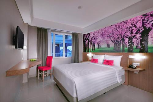 a bedroom with a bed and a desk and a window at The Vasini Hotel in Denpasar