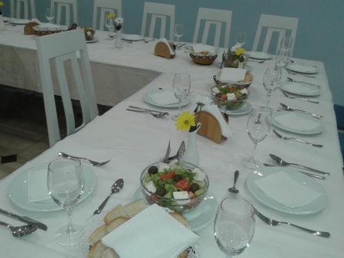 a table with plates and glasses and a bowl of salad at Capital Tirana Hotel Bruçi in Tirana