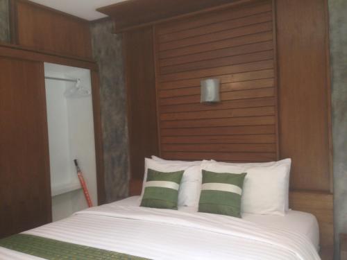 a bedroom with a bed with a wooden headboard and pillows at BaanPhong Lanta in Ko Lanta