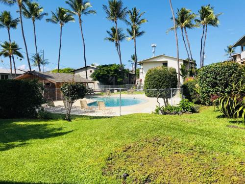 un patio con piscina y palmeras en Palani Condo, en Kailua-Kona