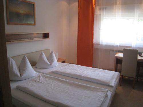 a bedroom with two beds and a table and a window at Hotel Barbarina in Tübingen