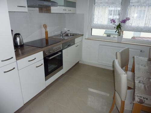 a white kitchen with a sink and a stove at Ferienwohnung Landwehr in Großostheim