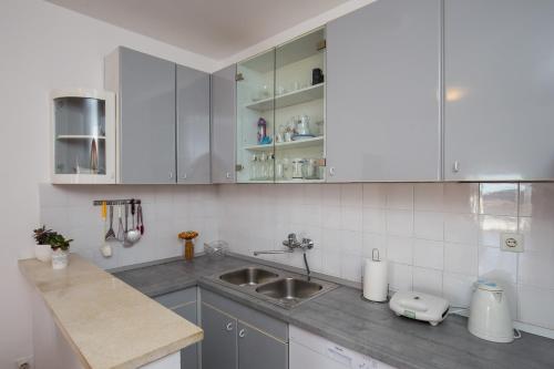 una cucina con armadi bianchi e lavandino di Apartment Jasna a Dubrovnik