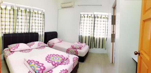 a room with two beds with pink pillows at Ipoh TZY's Homestay in Ipoh