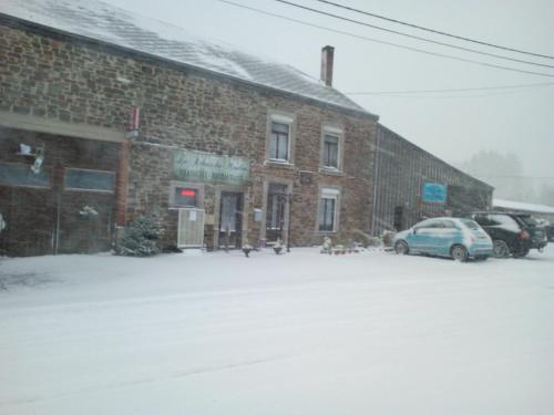 a snow covered parking lot in front of a brick building at Le Relais du Moulin in Gedinne