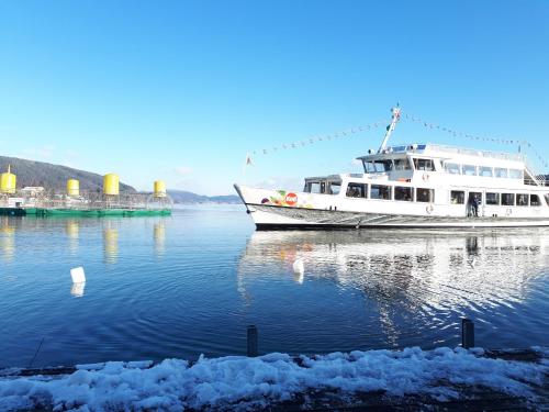 a boat is docked in the water next to snow at Boutiquehotel Wörthersee - Serviced Apartments in Velden am Wörthersee