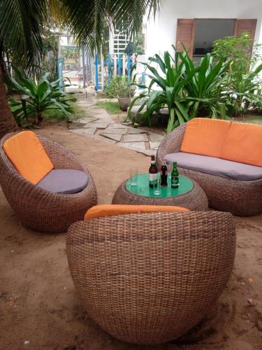 four wicker chairs and a table with bottles on it at Maison Tikani in Cotonou