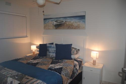 a bedroom with a bed with two lamps and a painting at 11 Coral Sands in Scottburgh