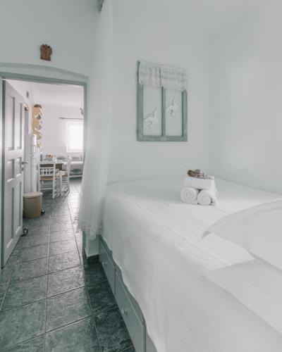 a white bedroom with a large bed and a table at Traditional Waterfront House in Mandrakia