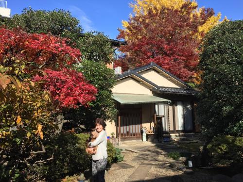 a man holding a child in front of a house at Mokkoan in Tokyo