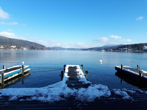 a dock on a lake with snow on the water at Boutiquehotel Wörthersee - Serviced Apartments in Velden am Wörthersee
