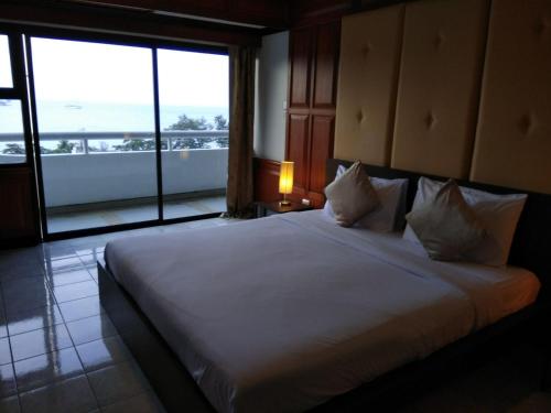 a bedroom with a large white bed with a large window at Patong Tower by United 21 Thailand in Patong Beach