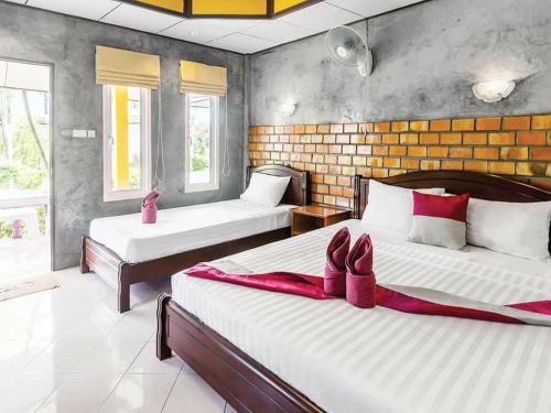 a bedroom with two beds with pink shoes on them at Lanta New Beach Bungalows - SHA Plus in Ko Lanta