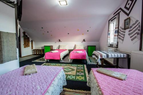 three beds in a room with pink sheets at Casa Lia in Valea Putnei
