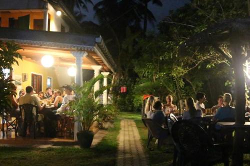 a group of people sitting outside of a restaurant at night at Plantation Surf Inn & Restaurant - Midigama in Midigama