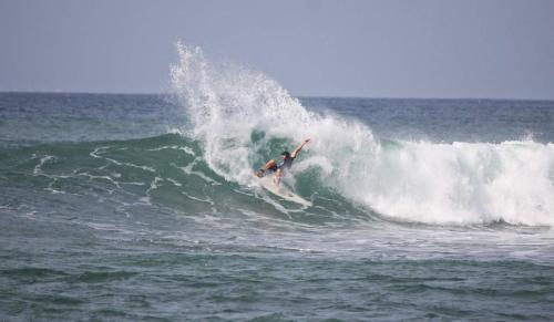 a man riding a wave on a surfboard in the ocean at Plantation Surf Inn & Restaurant - Midigama in Midigama