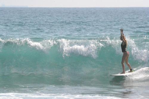 a woman riding a wave on a surfboard in the ocean at Plantation Surf Inn & Restaurant - Midigama in Midigama