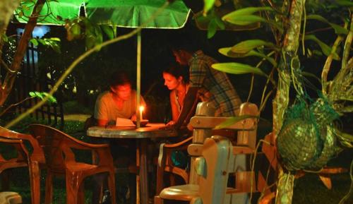 two people sitting at a table with a lit candle at Plantation Surf Inn & Restaurant - Midigama in Midigama