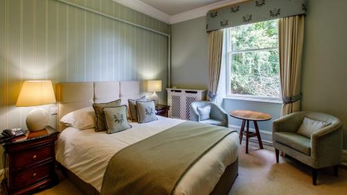 a bedroom with a bed and a chair and a window at Tor-Na-Coille Hotel in Banchory