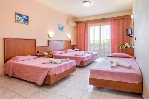 Habitación de hotel con 3 camas con sábanas rosas en Alea Hotel Apartments, en Ialisos