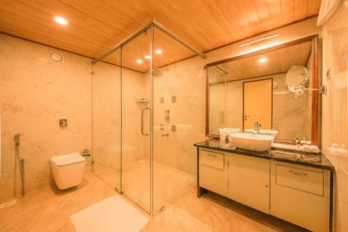 a bathroom with a shower and a sink and a toilet at White Lotus Hotel in Udupi