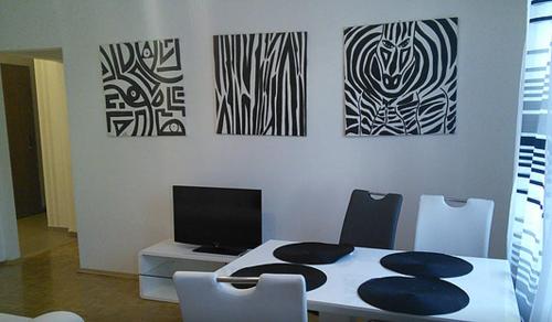 Design Home 1020 في فيينا: غرفة طعام مع طاولة وكراسي ولوحات