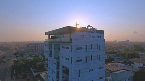 a building with the sun setting on top of it at Suncity Hotel Apartment in Accra