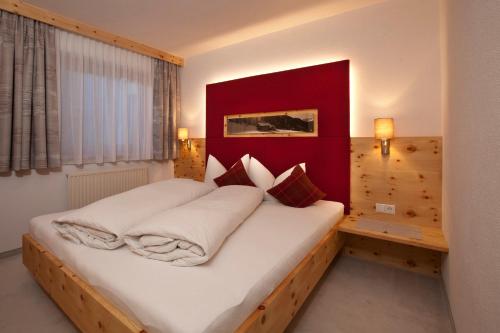 ナウダースにあるHaus Romanticaのベッドルーム1室(赤いヘッドボード付きの大型ベッド1台付)