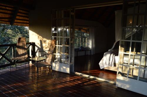 a room with a balcony with a bed and a glass door at Kruger River Villas - Mtombo in Marloth Park